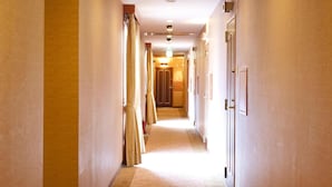 Pasillo de hotel con piso alfombrado, puertas a ambos lados y techo con iluminación empotrada.