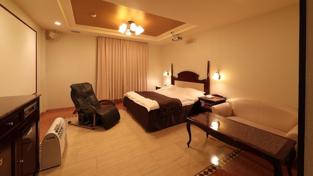 Una habitación de hotel con cama, sofá, escritorio, silla y proyector.