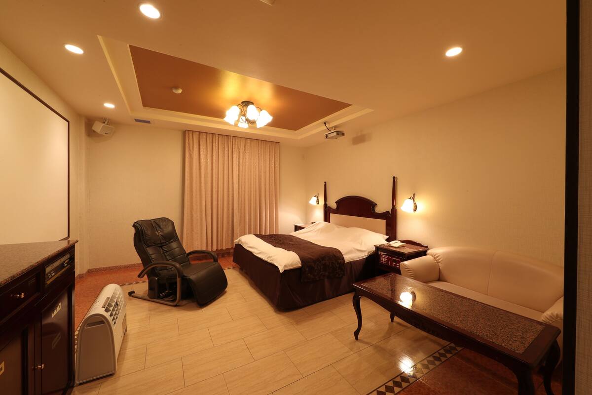 Una habitación de hotel con cama, sofá, escritorio, silla y proyector.