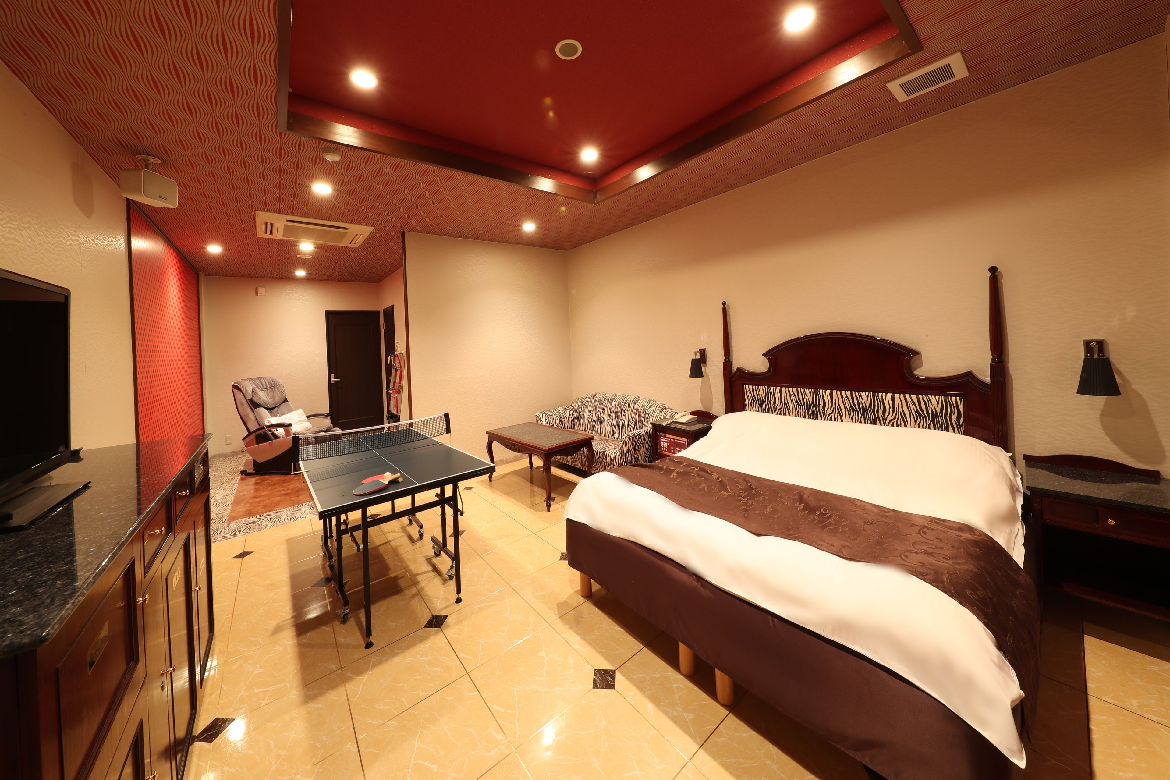 A hotel room with a bed, a desk, a chair, a table, and a television.
