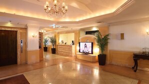 A hotel lobby with a reception desk, a television, potted plants, and a chandelier. - Fine Garden Nara Horai (Nara)
