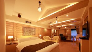 A spacious bedroom with a large bed, a sitting area with chairs, a fireplace, and a TV. - Fine Garden Nara Horai (Nara)