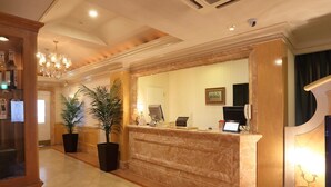 A hotel reception area with a marble counter, a reception desk, a computer, a telephone, and a potted plant. - Fine Garden Nara Horai (Nara)