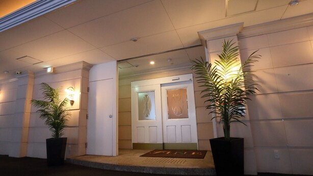 A hotel entrance with a double door, a doormat, and two potted plants. - Fine Garden Nara Horai (Nara)