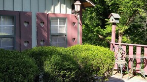 A building with a distinctive pink and white facade, a small porch with a bench, and a birdhouse on the right. - Hidden Springs Bed & Breakfast (Eureka Springs)
