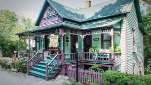 A Victorian-style house with a porch, steps, and a sign indicating it is a cottage. - Hidden Springs Bed & Breakfast (Eureka Springs)
