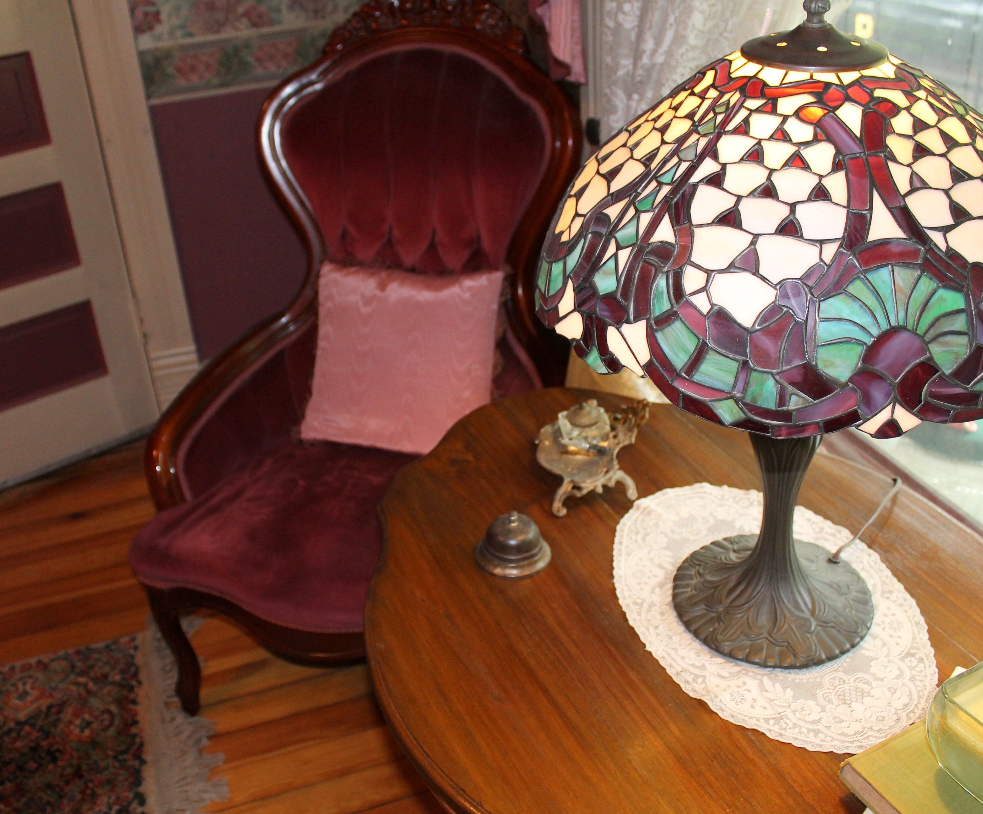A room with a wooden table, a decorative lamp, a chair, and a small figurine.