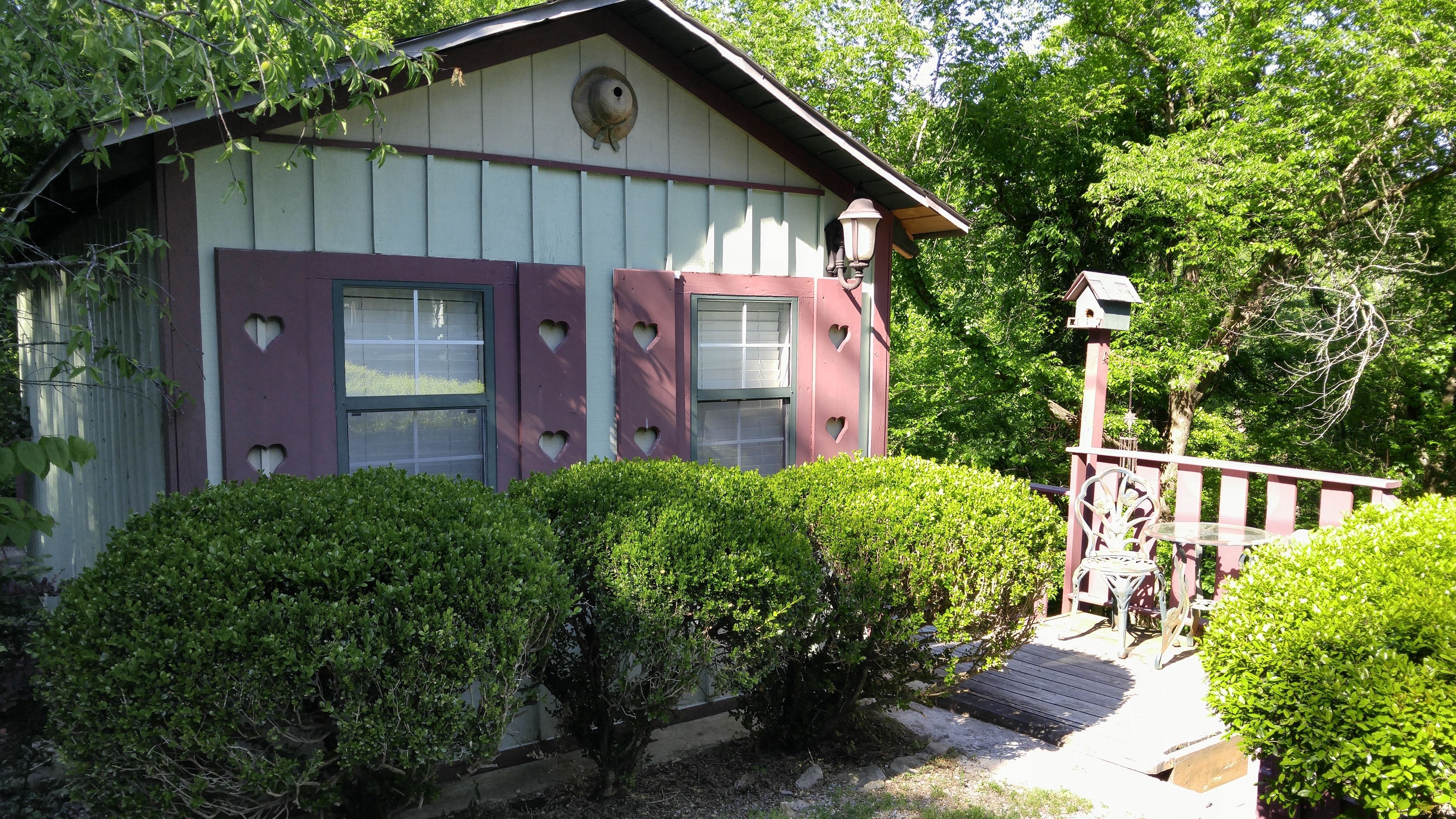 A house with heart-shaped window cutouts, a porch with a bench, and a small garden area.