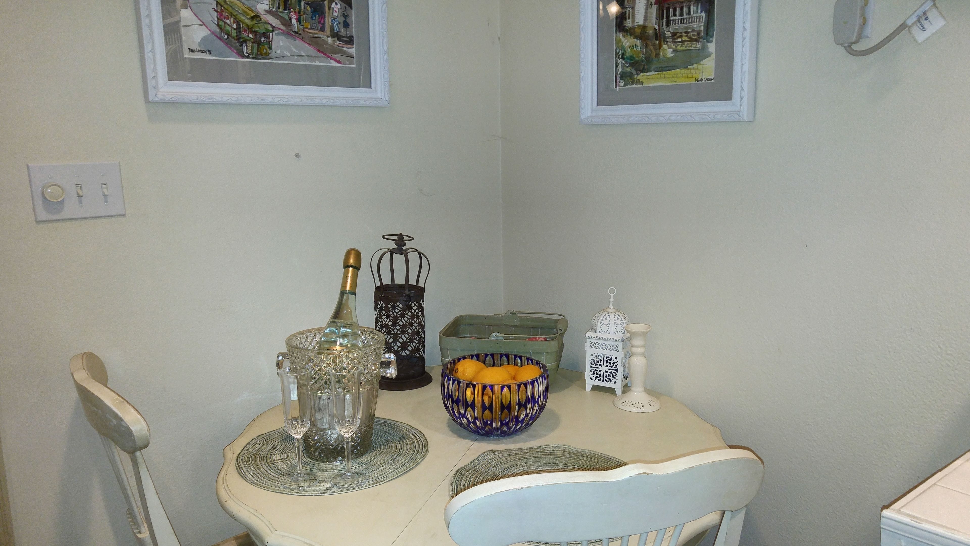 A dining table with a bottle, glasses, a lantern, and a decorative bowl.