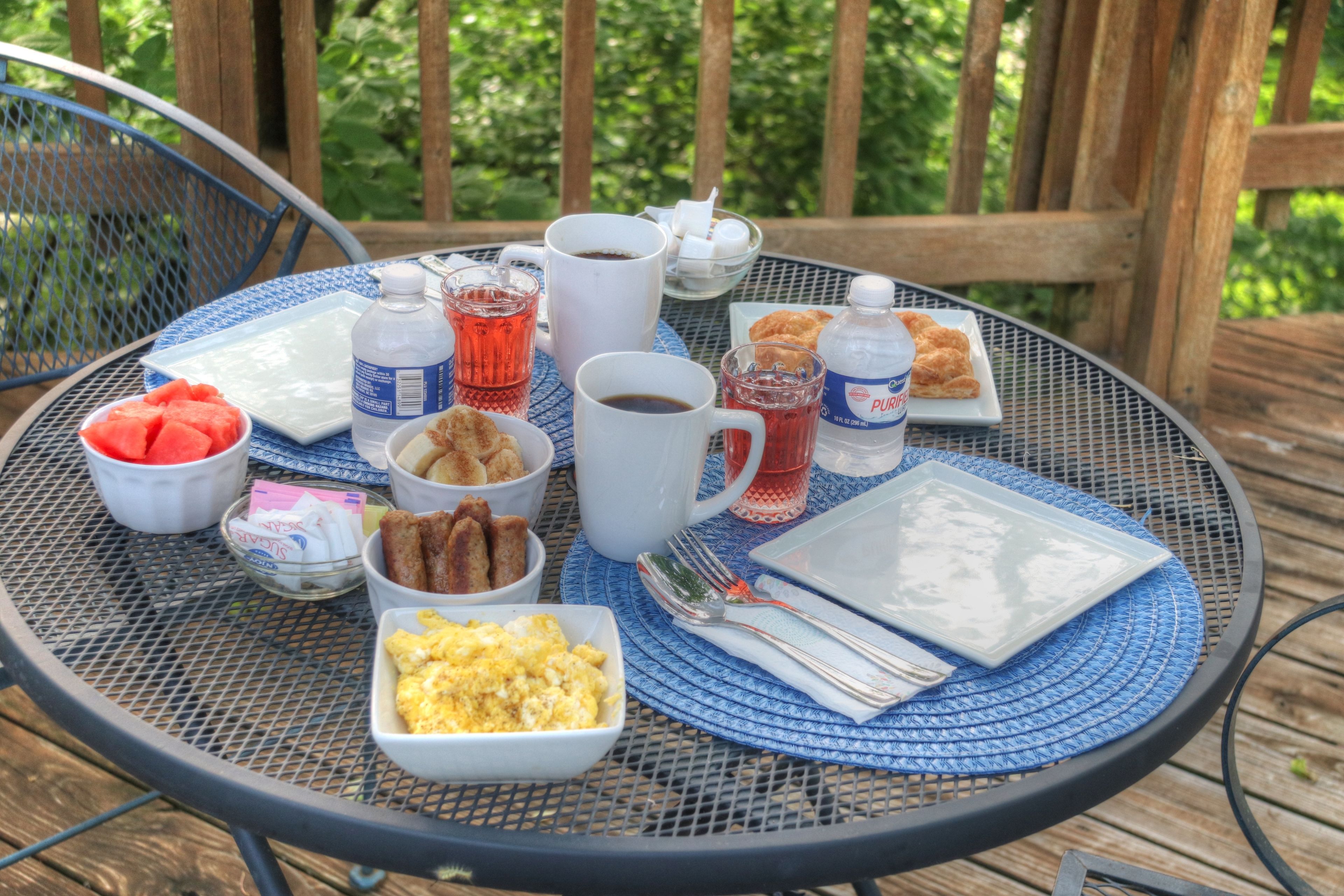 A round metal table with a blue placemat, set with breakfast items including eggs, toast, and juice.