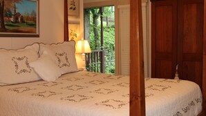A bedroom with a large bed, a nightstand with a lamp, a wooden wardrobe, and a painting on the wall. - Hidden Springs Bed & Breakfast (Eureka Springs)