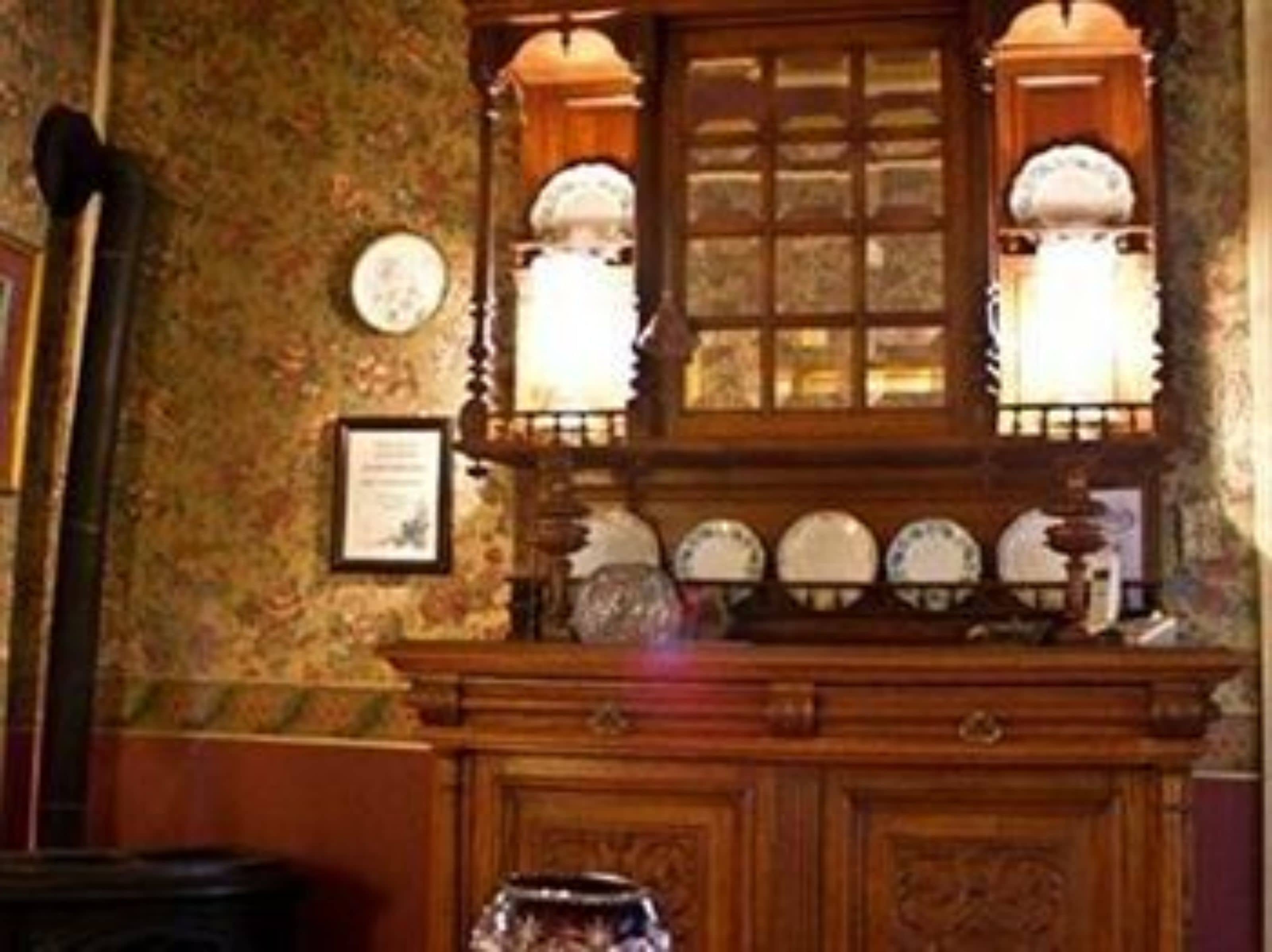 A room with a wooden cabinet, a mirror, and a wall-mounted clock.