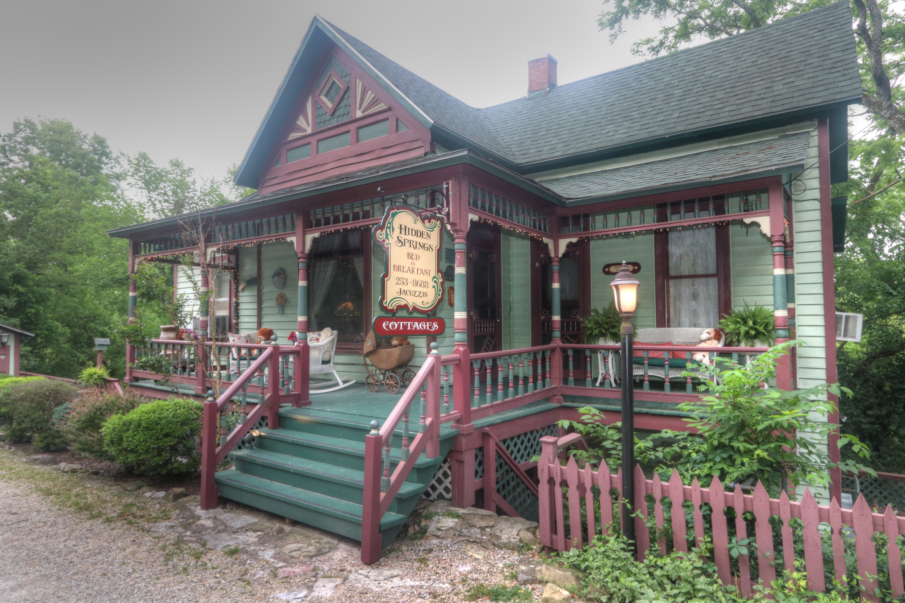 A traditional wooden building with a porch, steps, and a sign indicating it is a bed and breakfast.