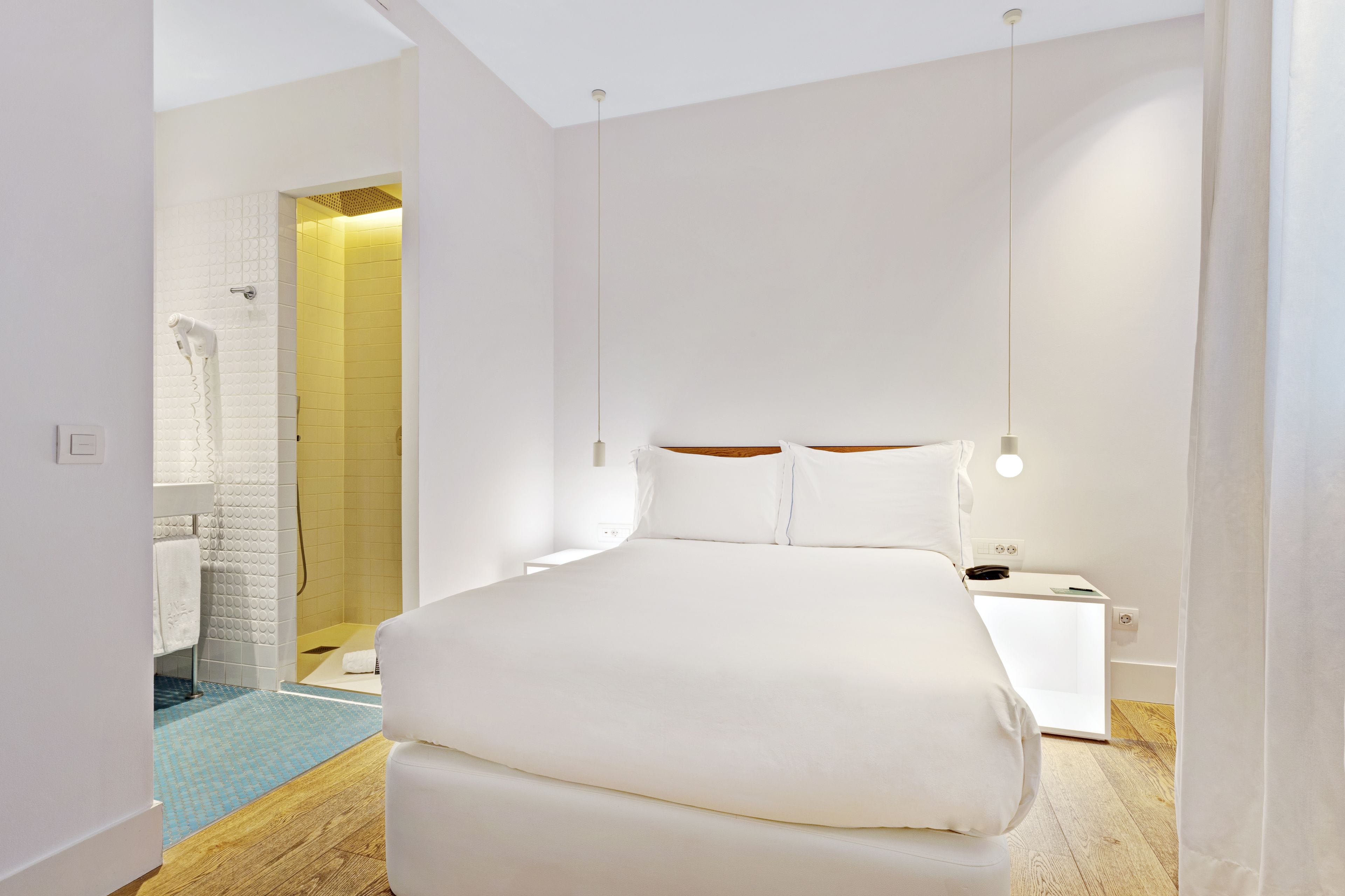 Une chambre moderne avec un grand lit, des tables de chevet, une commode et un dressing.