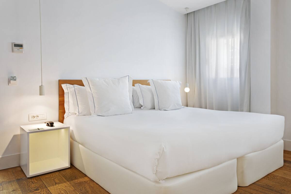 A neatly arranged bedroom with a large bed, a bedside table, and a nightstand.