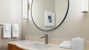 Un baño con un espejo grande, un lavabo y un mueble de tocador de madera.