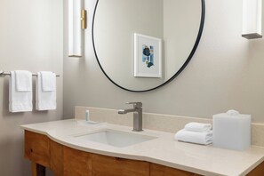 Un baño con un espejo grande, un lavabo y un mueble de tocador de madera.