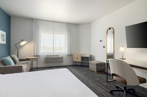 A hotel room with a bed, a desk, a chair, a television, and a window with curtains.