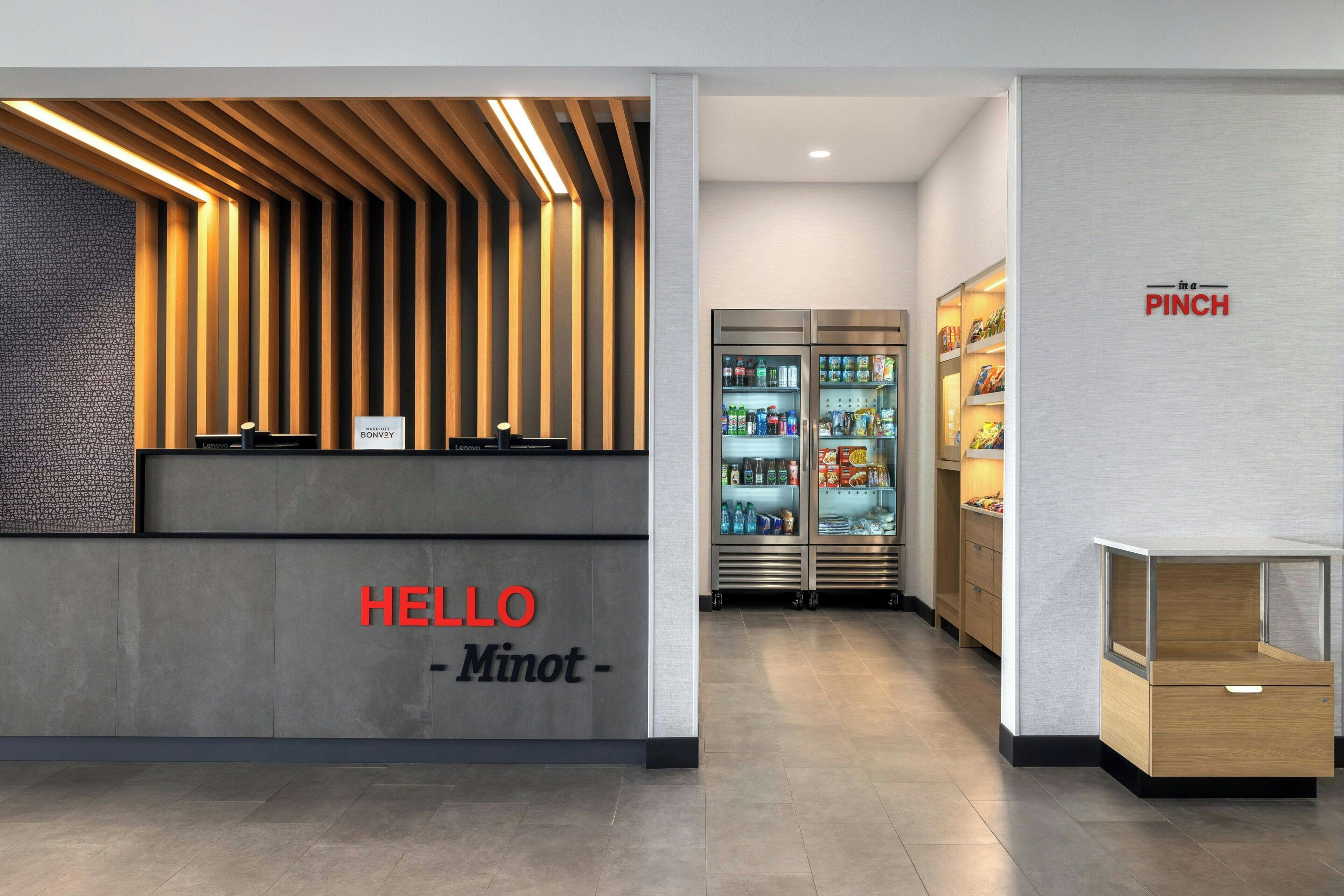 Una recepción de diseño moderno, un cartel que dice 'HELLO - Minot -' y un cartel en la pared con la palabra 'PINCH'.