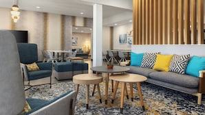 Un espacio lounge moderno con asientos, mesas y una pared decorativa.