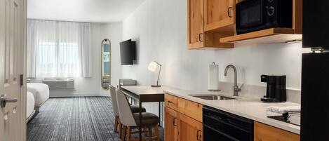 Une chambre d’hôtel compacte comprenant un coin cuisine, un espace repas et un lit.