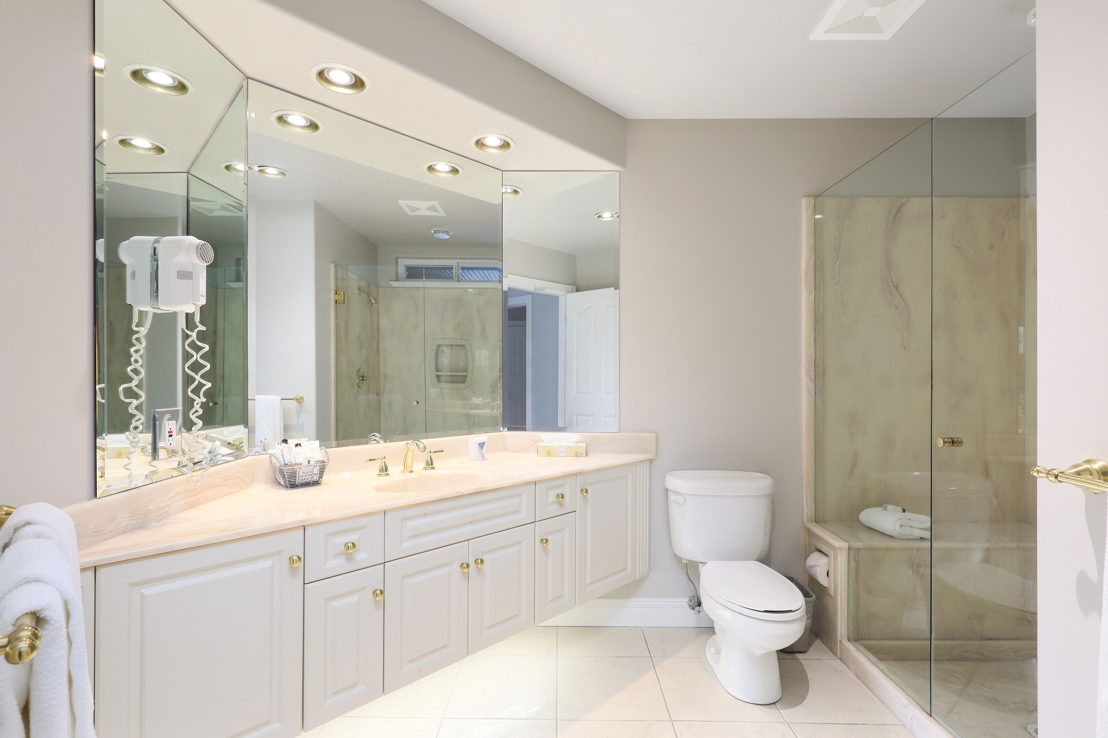 A modern bathroom with a large mirror, a glass shower enclosure, and a white toilet.