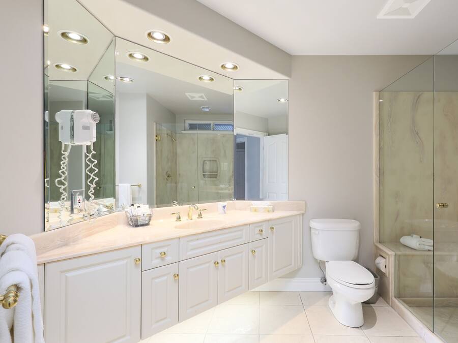 A modern bathroom with a large mirror, a glass shower enclosure, and a white toilet.