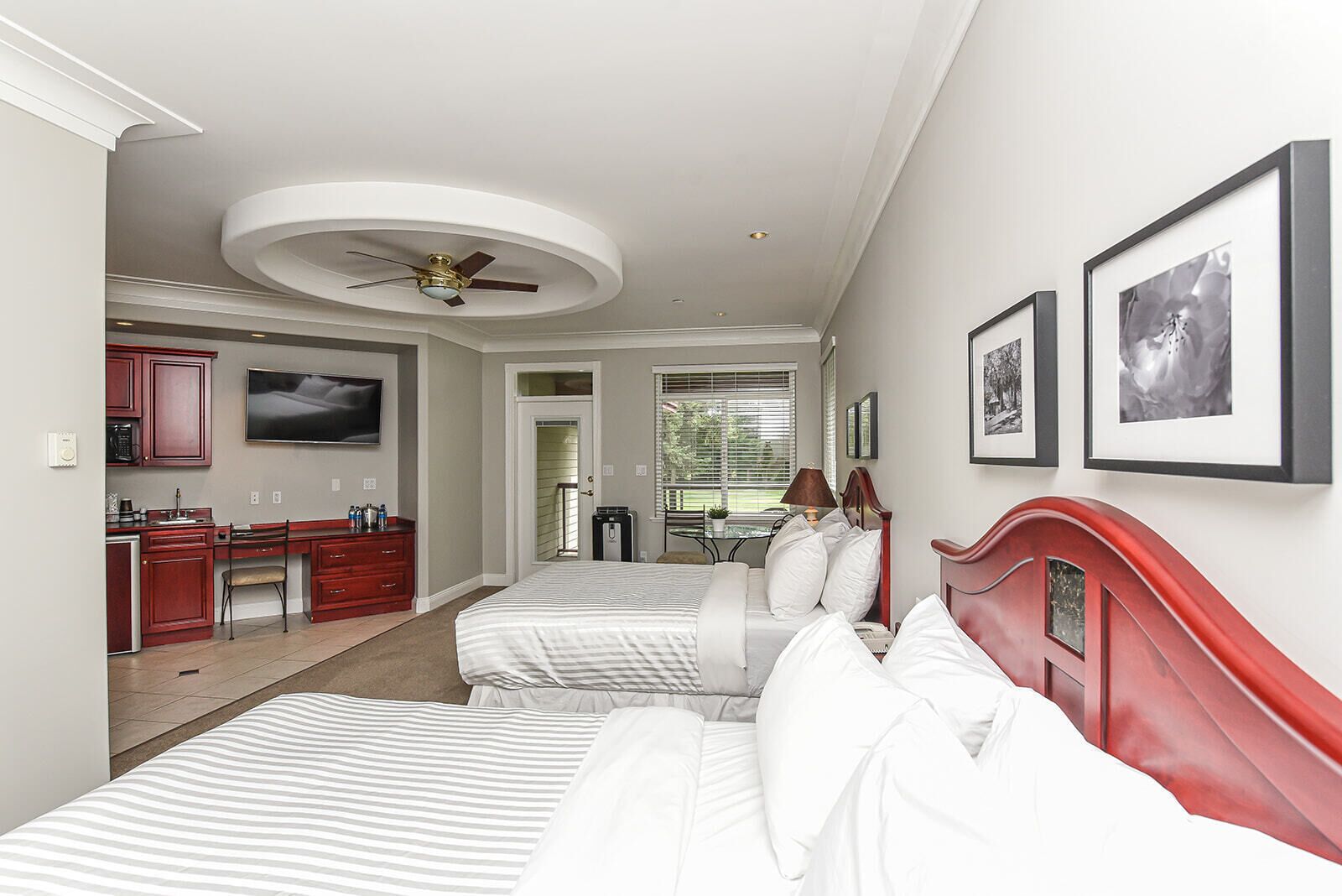 A bedroom with two beds, a desk, and a ceiling fan.