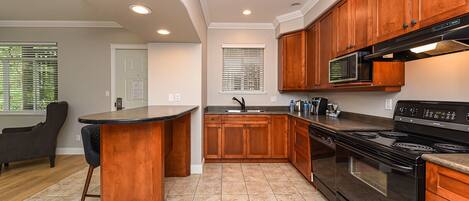 A modern kitchen with wooden cabinets, a black stove, and a microwave.