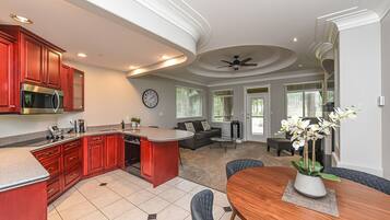 A modern kitchen with red cabinets, a microwave, and a dining area with a wooden table and chairs.