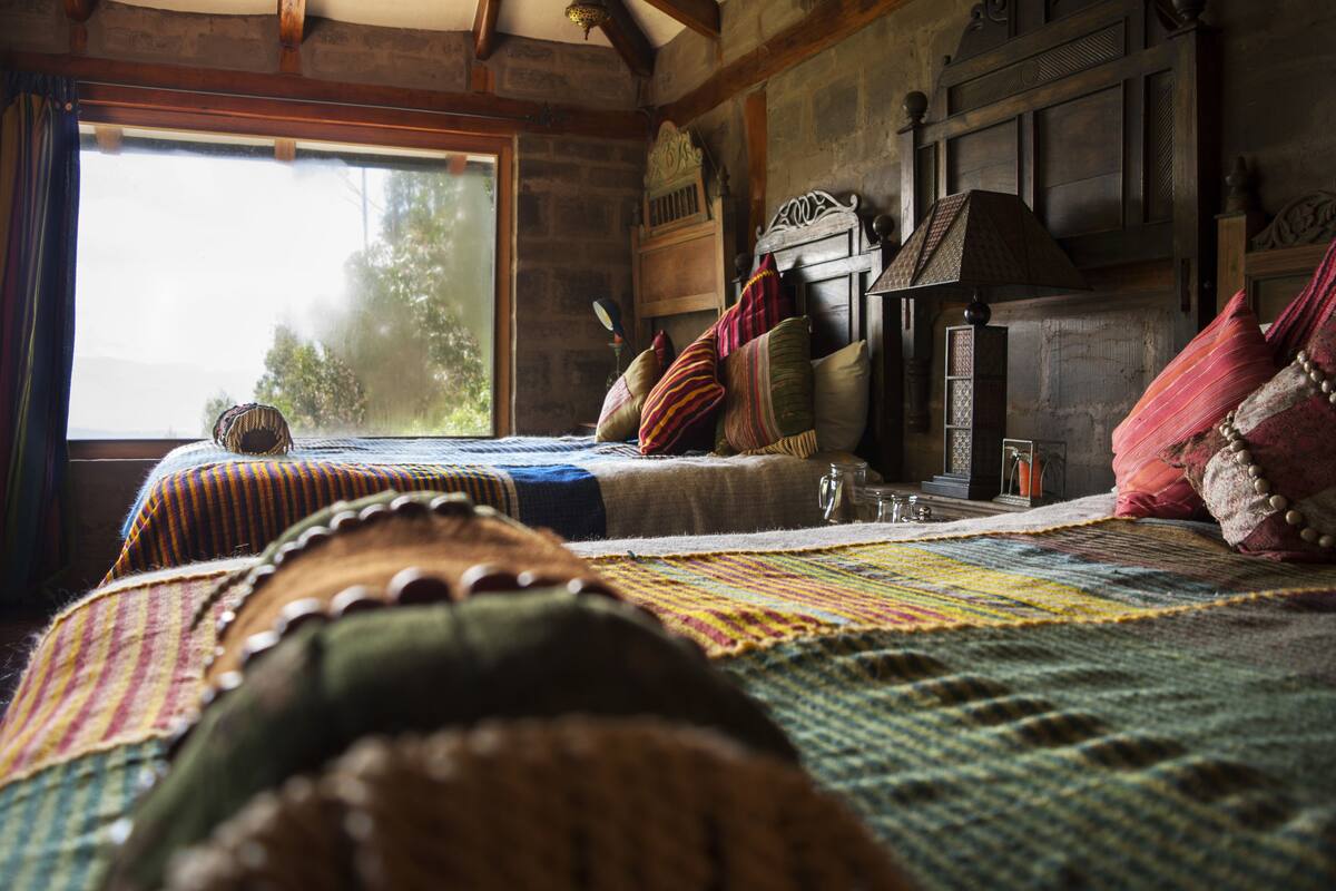 A cozy room with a large bed, a wooden headboard, and a window with curtains.