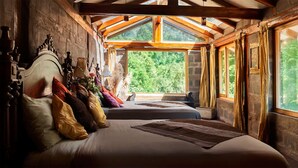 Un dormitorio con un ventanal grande, vigas de madera y una cama con muchas almohadas.