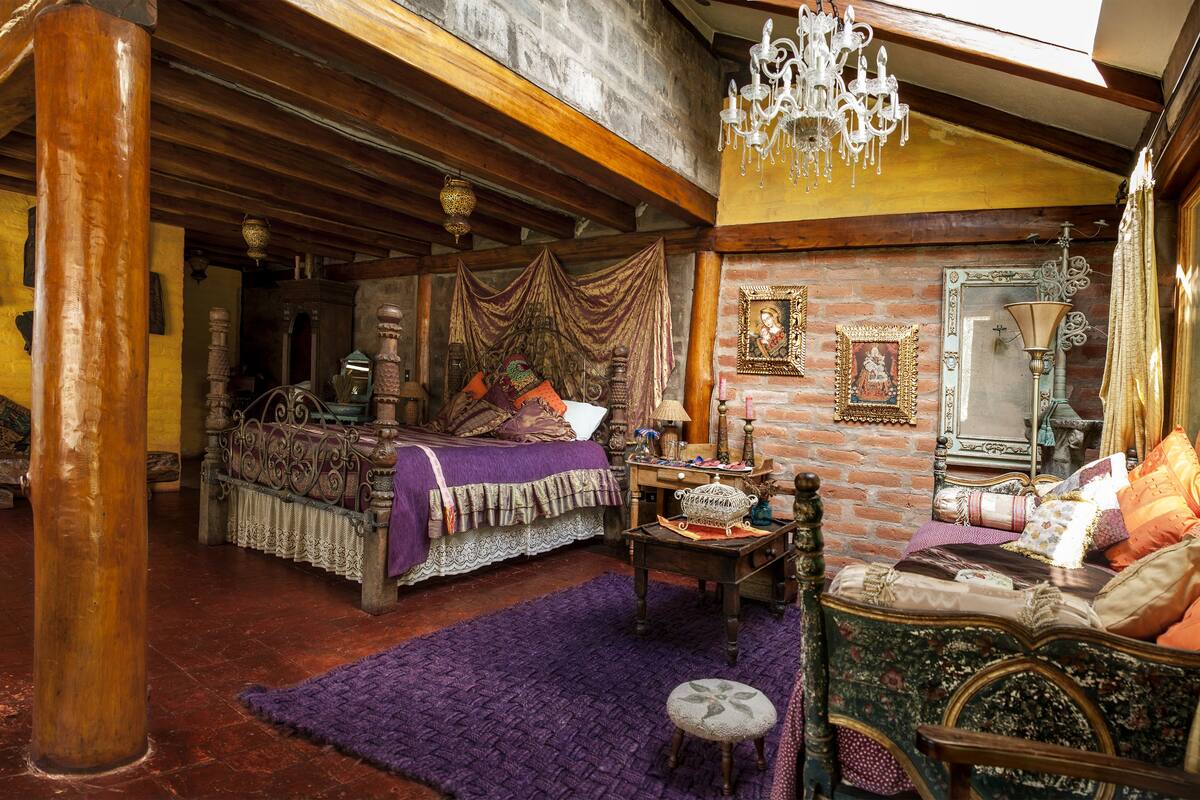 A traditional room with a bed, wooden beams, a chandelier, and a mirror.
