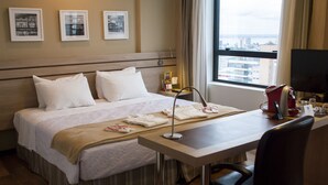 A hotel room with a bed, a desk, a chair, a window with a city view, and framed pictures on the wall. - Hotel Intercity Manaus (Manaus)