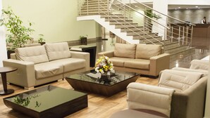 A modern hotel lobby with beige sofas, a glass coffee table, and a staircase leading to the upper floor. - Hotel Intercity Manaus (Manaus)
