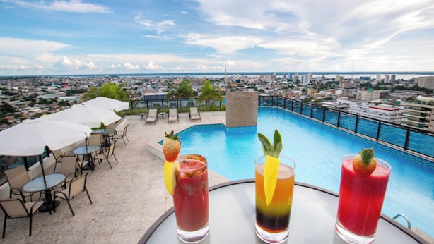 A rooftop bar with a pool view, outdoor seating, and three drinks on a table. - Hotel Intercity Manaus (Manaus)