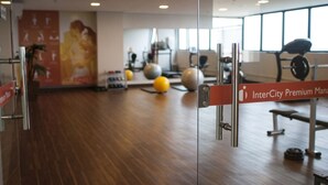 A gym with exercise equipment, a wooden floor, and a wall with a large poster. - Hotel Intercity Manaus (Manaus)