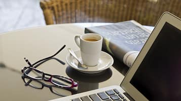 Un ordenador portátil, una taza de café, un par de gafas y un libro sobre una mesa.