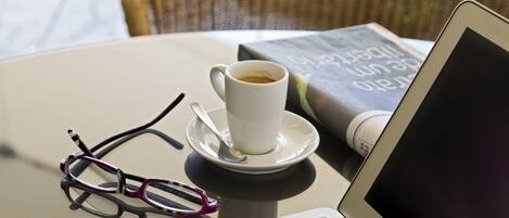 Un ordenador portátil, una taza de café, un par de gafas y un libro sobre una mesa.