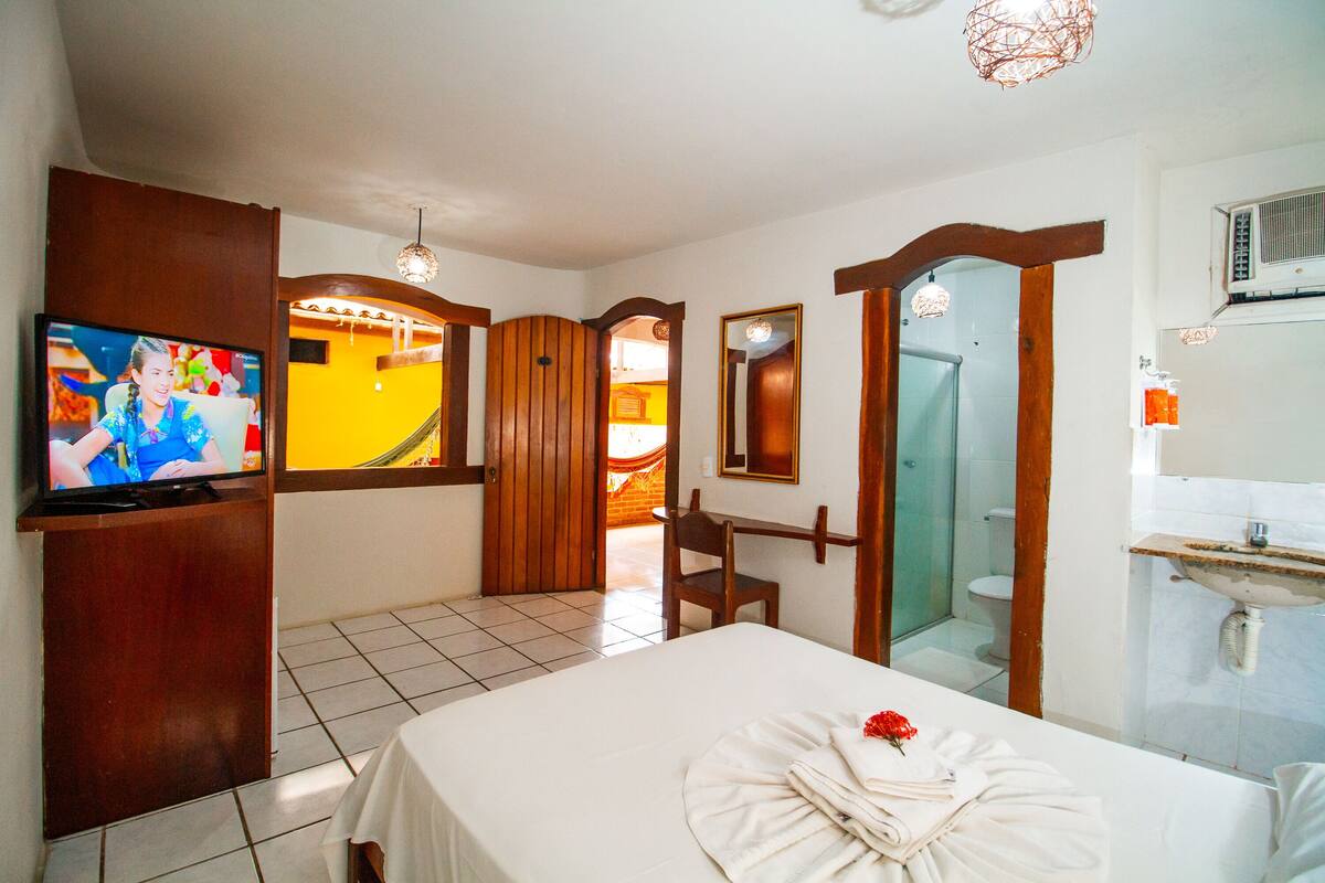 A hotel room with a bed, a TV, a bathroom, and a shower.