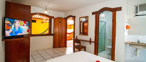 A hotel room with a bed, a TV, a bathroom, and a shower.