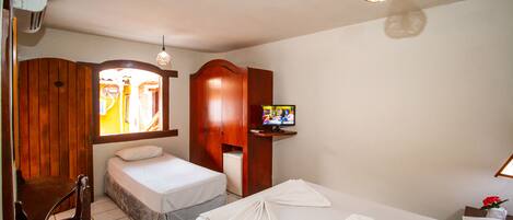 A hotel room with two beds, a TV, wooden furniture, and a small TV stand.