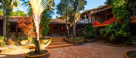 A courtyard with a palm tree, brick steps, and a building with a red and yellow facade.