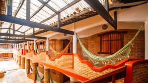 Un edificio tradicional con varias hamacas colgadas entre vigas de madera y paredes de ladrillo.