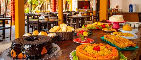 A buffet table with various dishes, including a chocolate cake, a vegetable salad, and several bread items.