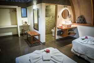 Un cuarto de spa con un banco de madera, una mesita, un espejo, un lavamanos y una toalla con un flor.