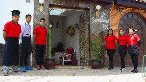 A group of people in red shirts standing outside a building with a sign that reads "Sambla Inn." - Casa La Sambleña INN (Cusco)