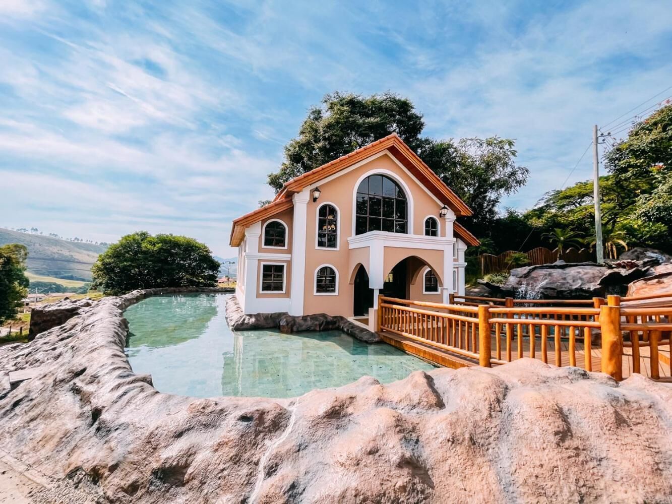 A building with a large arched window, a stone bridge, and a pool.