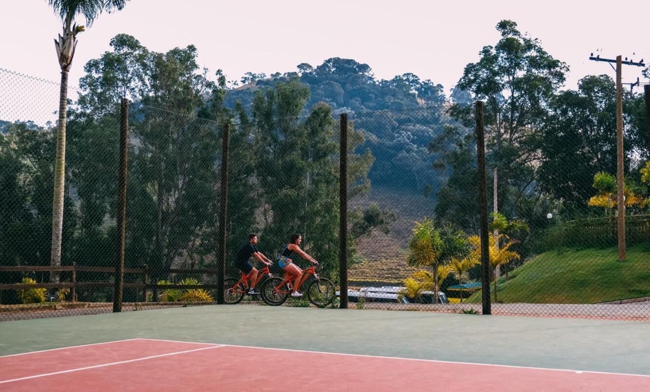 A tennis court with two cyclists riding on it.