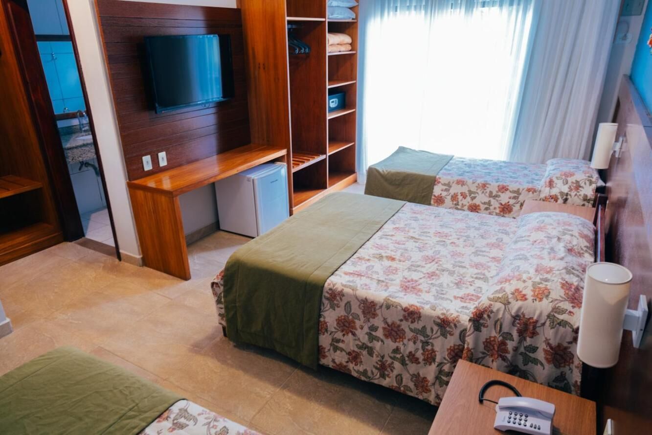 Een hotelkamer met twee bedden, een televisie, een bureau en een telefoon.